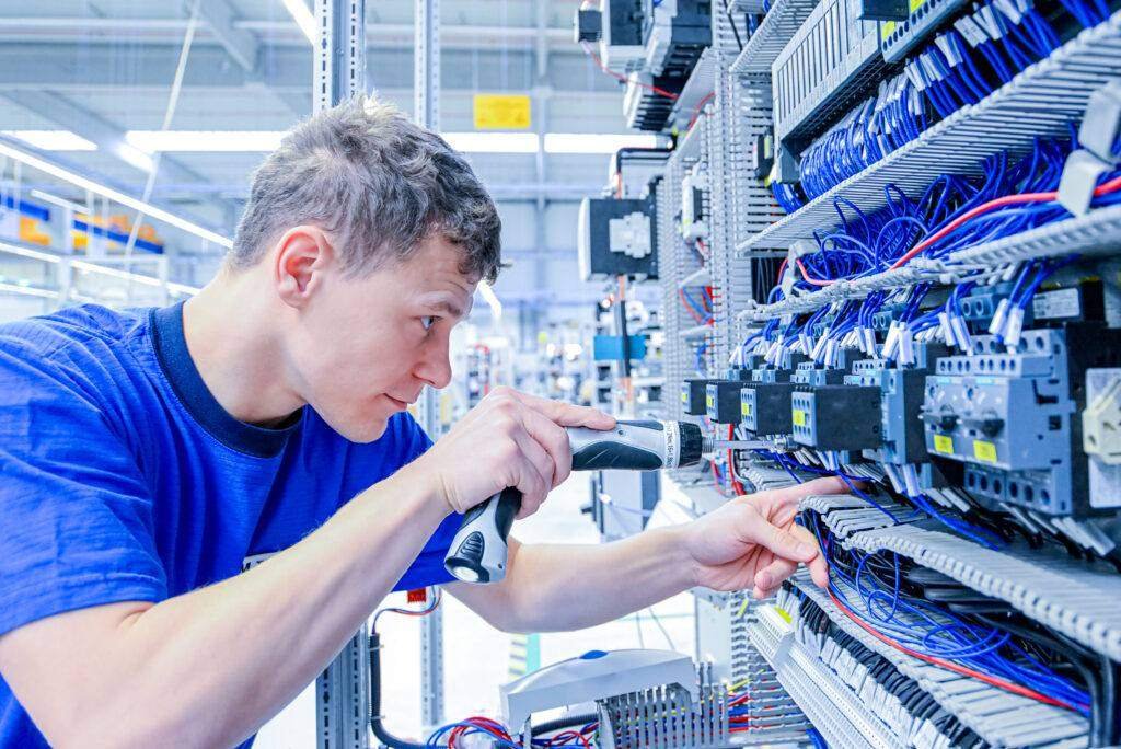 EUCALEX engineer checking wiring inside an industrial control cabinet