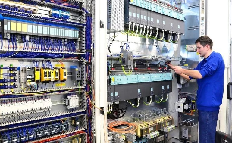 Apprentice engineer measuring on an industrial control panel